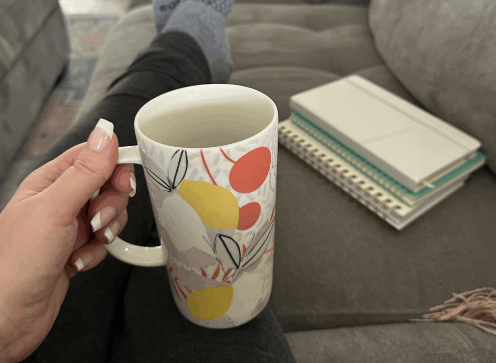 Picture of a woman holding a mug on a couch with notebooks for a business owner's quarterly planning retreat