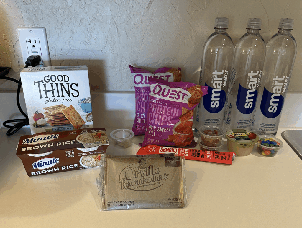 Picture of a hotel counter top with water bottles, chips, crackers, popcorn, apple sauce, and rice for a small business owner quarterly planning retreat.