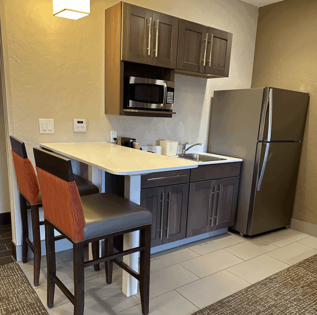 Picture of a hotel room kitchen with a refrigerator, microwave, sink, and bar for a small business owner quarterly planning retreat.